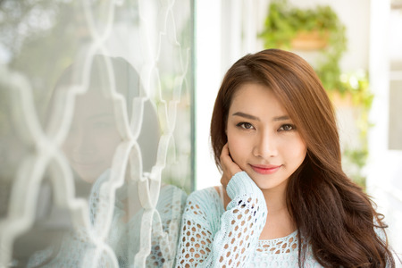 Young asian woman relaxing on a balcony  enjoying fresh air.の写真素材
