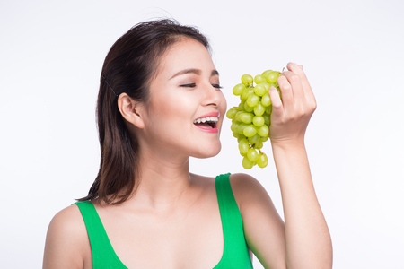 Young beautiful asian woman eating fresh grapes isolated on white backgroundの写真素材