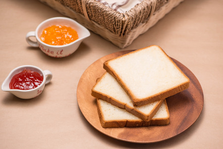 Toast with strawberry and orange jam on a plate on table.の写真素材