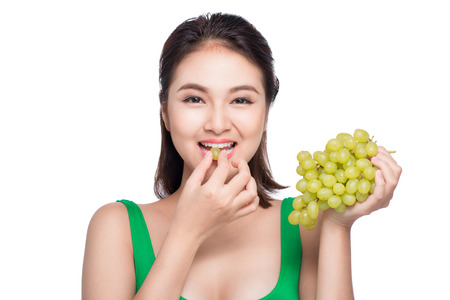 Young beautiful asian woman eating fresh grapes isolated on white backgroundの写真素材
