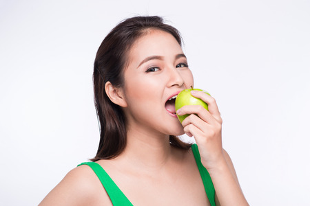 Attractive smiling young asian woman eating green apple isolated over white background.の写真素材