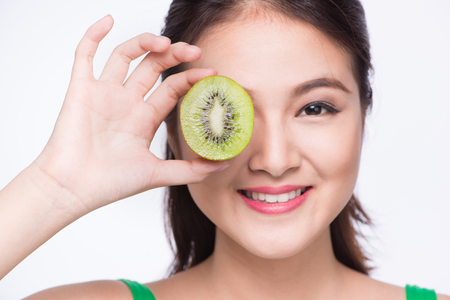 Kiwi fruit. Happy young asian woman holding kiwi fruit isolated on white backgroundの写真素材