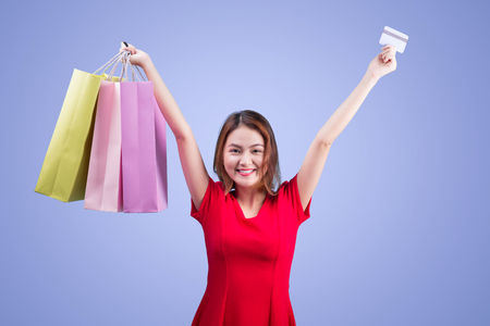 Santa asian woman holding shopping bags and credit card against violetの写真素材