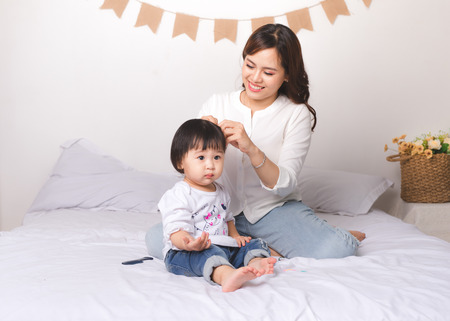 Happy loving family. Mom and child girl are having fun on the bed.の写真素材