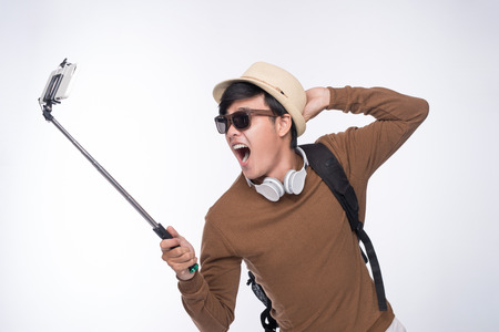 Happy young asian man taking self portrait photography through smart phoneの写真素材