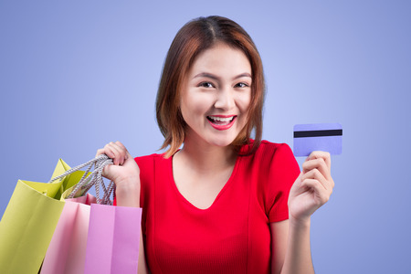 Santa asian woman holding shopping bags and credit card against violetの写真素材