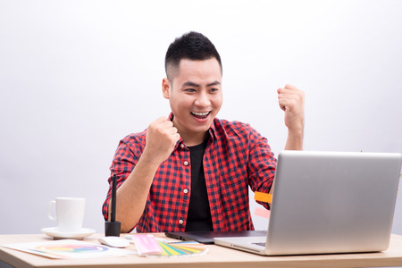 Happy designer working on his laptop in creative officeの写真素材