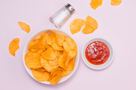 Concept of unhealthy food. Cheese and onion potato chips with hot chilli sauce on pink background.の写真素材