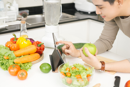Young asian handsome man preparing food in kitchen at homeの写真素材