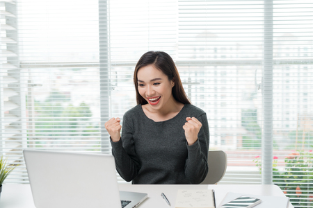 Single young excited woman celebrating something with both arms extended upwardの写真素材