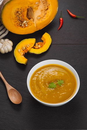 Bowl of pumpkin soup on black stone background.の写真素材