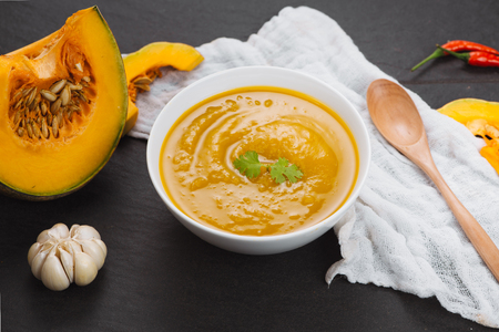 Pumpkin soup in a bowl with fresh pumpkins, garlic and parsley herbsの写真素材