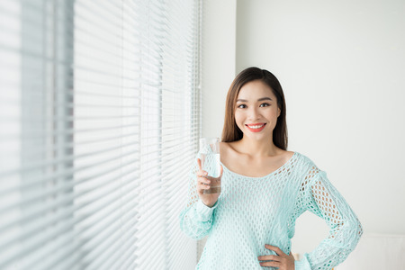 Beautiful asian girl drinking water at homeの写真素材