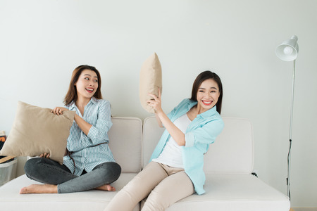 Friends having fun on the couch and making pillow fightの写真素材