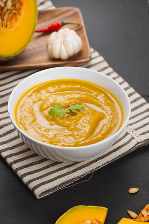 Bowl of pumpkin soup on black stone background.の写真素材