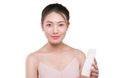 Gorgeous asian woman smiling and holding face cream. Studio shot. Horizontalの写真素材