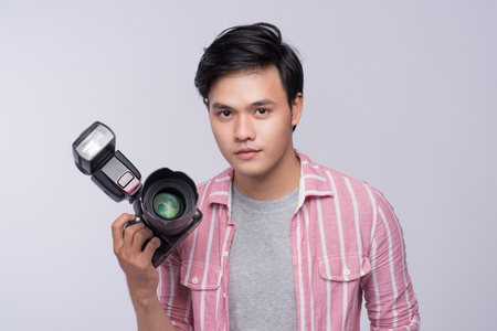Young asian photographer holding digital camera, while working in studioの写真素材