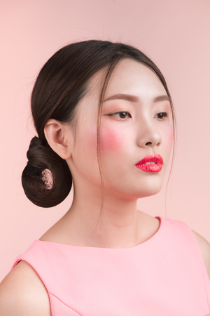 Beauty fashion portrait. Smiling young asian woman on pink background.の写真素材