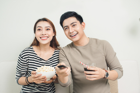 Attractive couple watching tv on the couch at home in living roomの写真素材