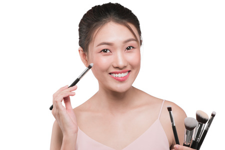 Portrait of attractive young asian woman holding make-up brushs over whiteの写真素材