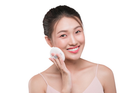Portrait of beautiful young asian model applying some powder using powder puffの写真素材