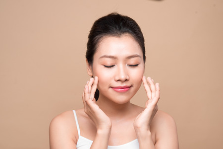 Beauty face. Facial treatment. Young asian woman with clean perfect skin touch her face.の写真素材