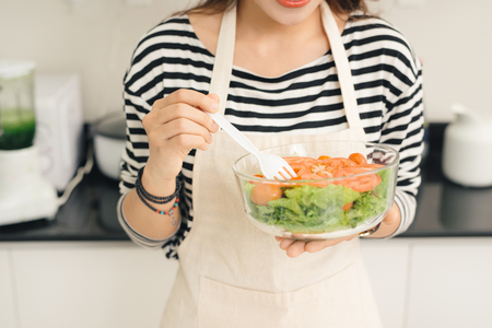 Young happy woman eating salad. Healthy lifestyle with green food.の写真素材