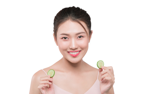 Young asian woman with cucumber slice in her hands isolated on white backgroundの写真素材