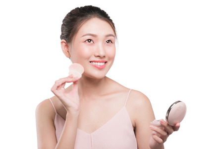 Portrait of beautiful young asian woman with perfect fresh clean applying blusher to her cheekの写真素材
