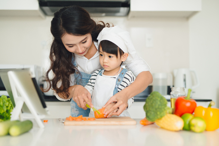 Mother with her daughter preparing lunch in the kitchen and enjoying together.の写真素材