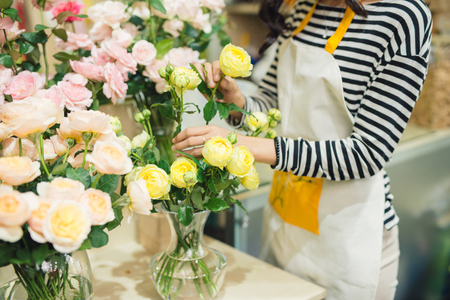 Young beautiful asian girl florist taking care of flowers at workplace.の写真素材