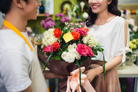 Male florist offering flowers at the counter in the florist shopの写真素材