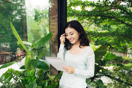 Young attractive sweet girl with notepad on a veranda. Spring mood.の写真素材