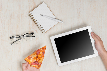 Man holding a digital tablet and tasty pizza with ingredients on wooden table.の写真素材
