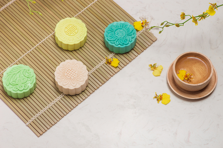 Sweet color of snow skin mooncake. Traditional mid autumn festival foods with tea on table setting.の写真素材
