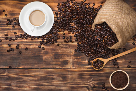 Coffee beans in spoon and cup of hot drinkの写真素材