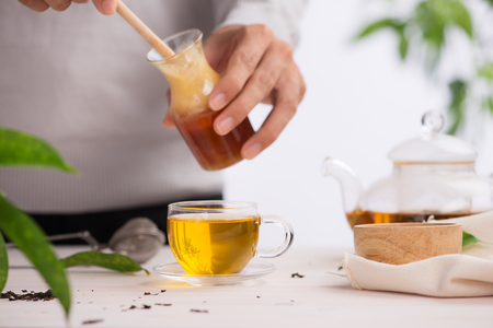 Cropped image of arista pouring honey into cup of teaの写真素材
