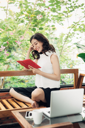 Beautiful asian girl writing notes in a desk at homeの写真素材