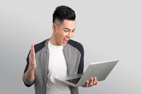 Confident young asian businessman holding laptopの写真素材