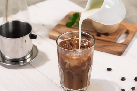 Bartender pours milk into glass of coffeeの写真素材
