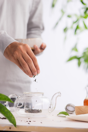 Male hands with dry black tea fallingの写真素材