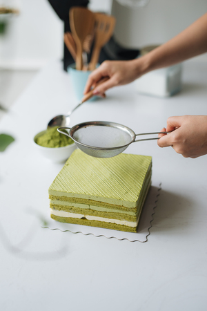 Pour green tea powder over delicious cheesecakeの写真素材