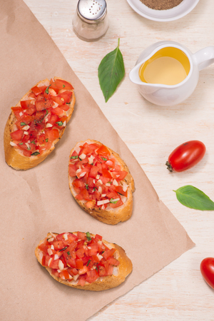Italian bruschetta with roasted tomatoes, mozzarella cheese and herbs on a paperの写真素材