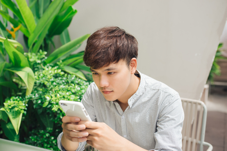 Young handsome businessman texting on smartphone in comfortable coffee shopの写真素材