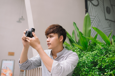 Young man photographer taking picture sitting at table in coffee shopの写真素材