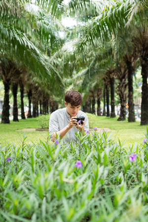 Young asian man photographer taking picturein parkの写真素材