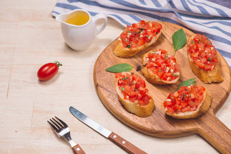 Italian bruschetta with roasted tomatoes, mozzarella cheese and herbs on a cutting boardの写真素材