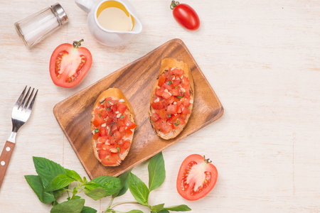 Preparing delicious Italian tomato bruschetta with chopped vegetables, herbs and oilの写真素材