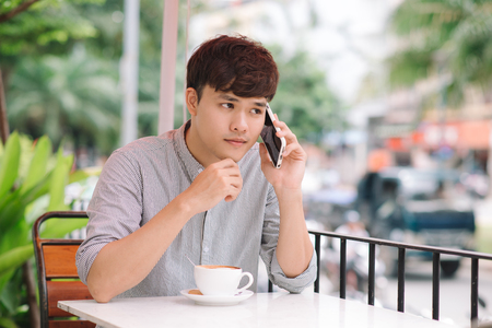 Young handsome businessman making phone call in cafe indoorsの写真素材