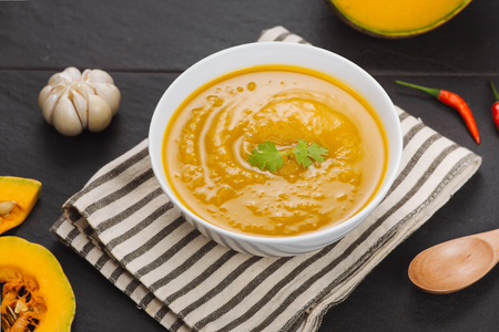 Bowl of pumpkin soup on black stone background.の写真素材